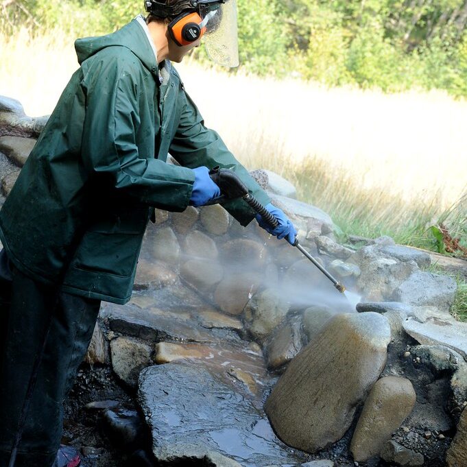 man pressure washing rocks